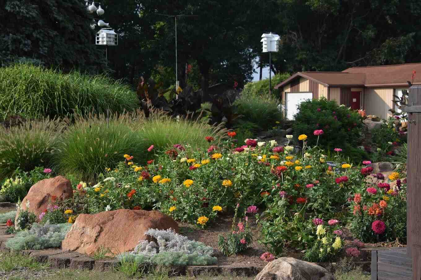 A vibrant flower garden with colorful blooms, lush greenery, and birdhouses, enhancing the scenic beauty of River Lake Inn Restaurant.